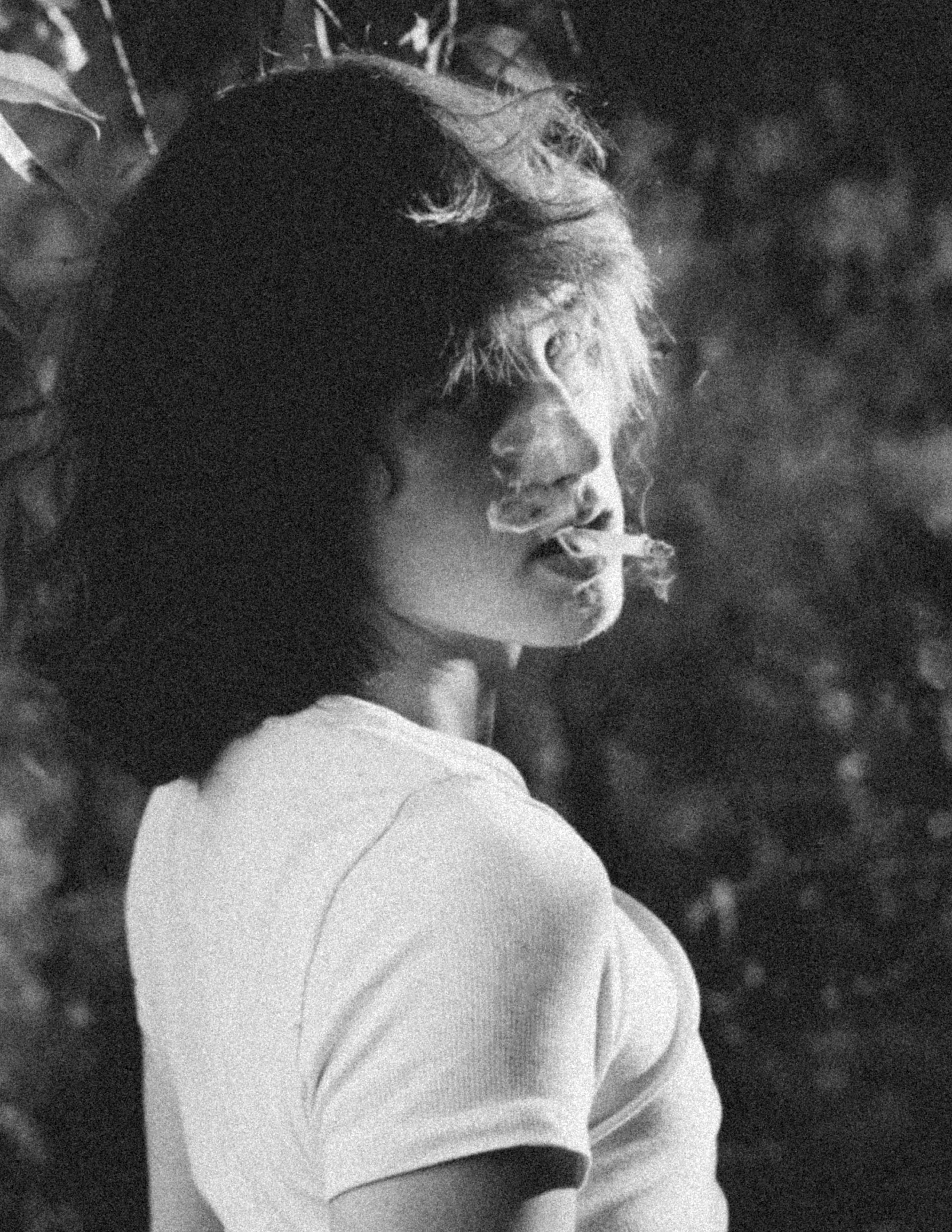 Black and white portrait of a woman with curly hair smoking