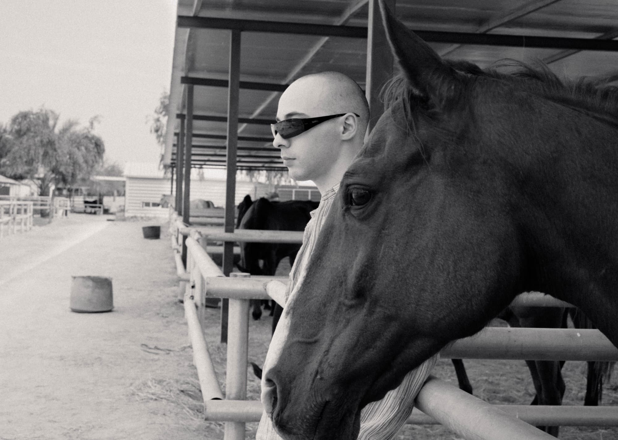 Black and white portrait of a man in sunglasses beside a horse