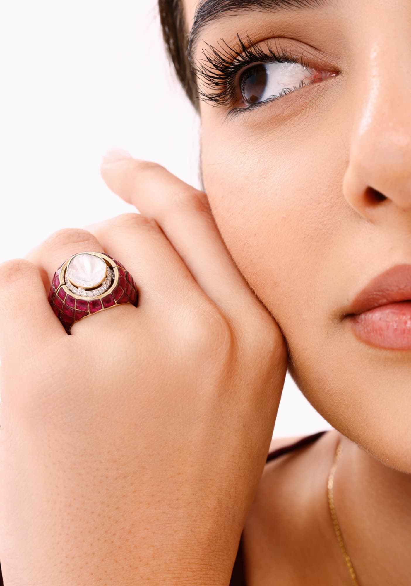 Close-up of a woman's face and a ruby ring