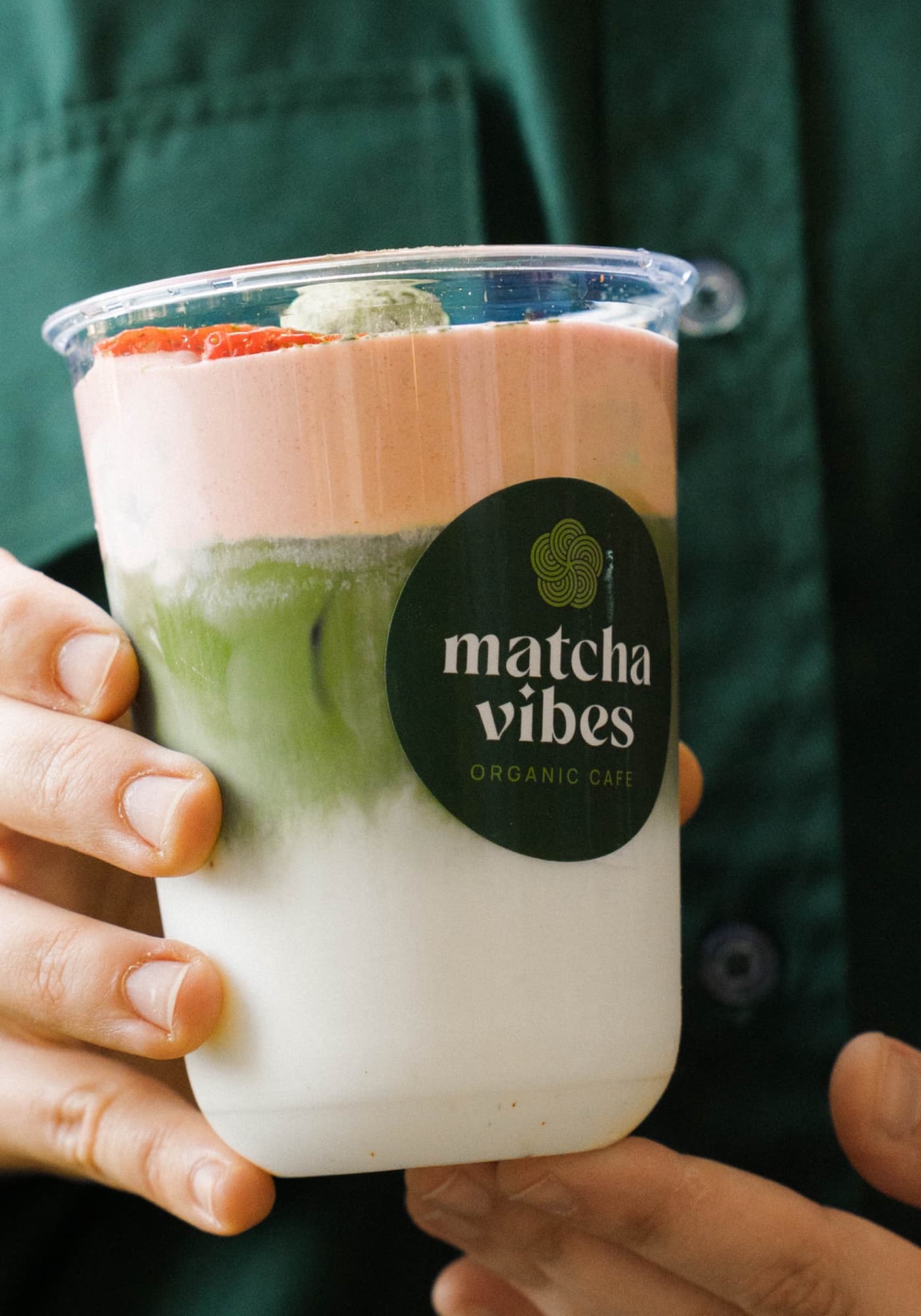 Hands holding a layered matcha drink