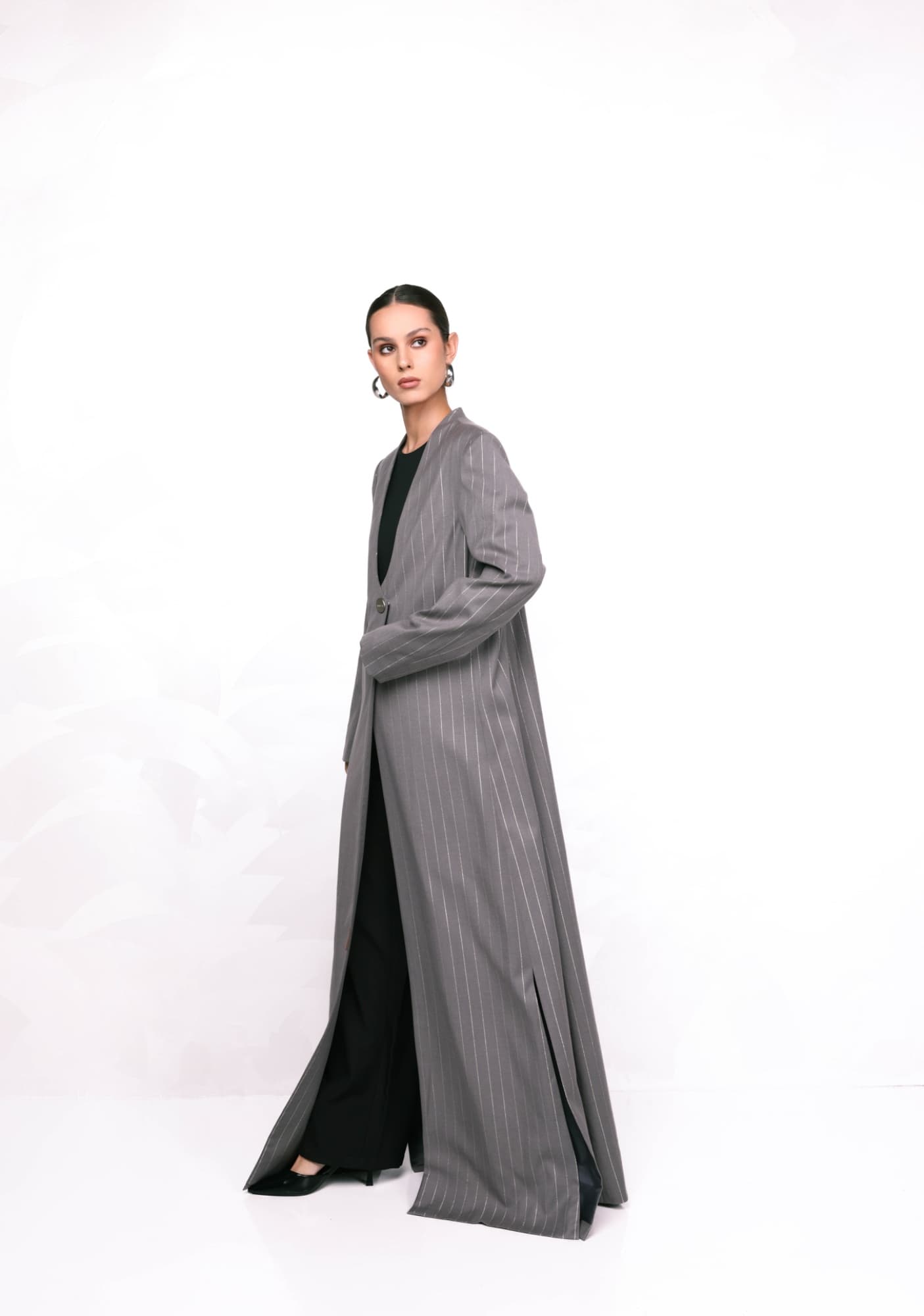 Model in a long grey coat on a white studio background
